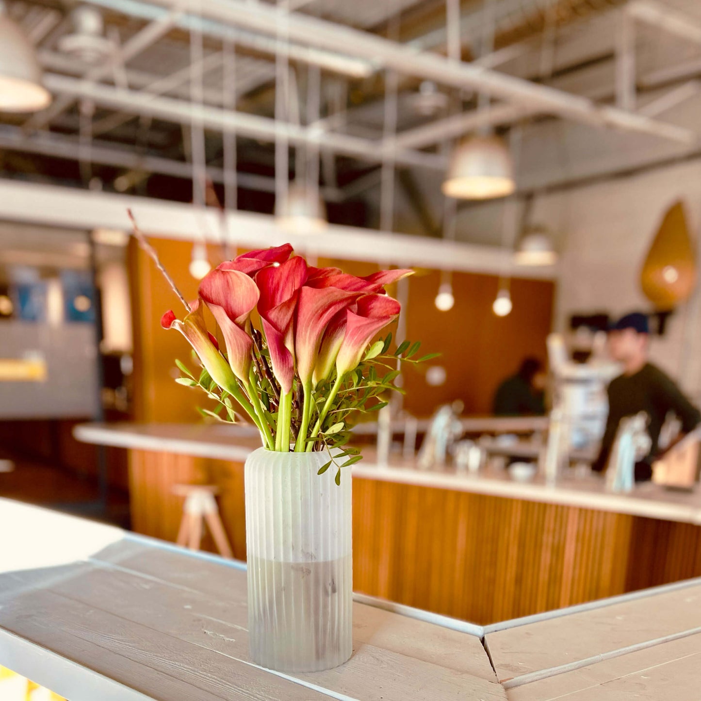 Medium tabletop arrangement – red lilies – for a workplace countertop, workplace weeklies for B2B flowers in Toronto, Quince Flowers – Toronto’s best B2B florist, available near you.
