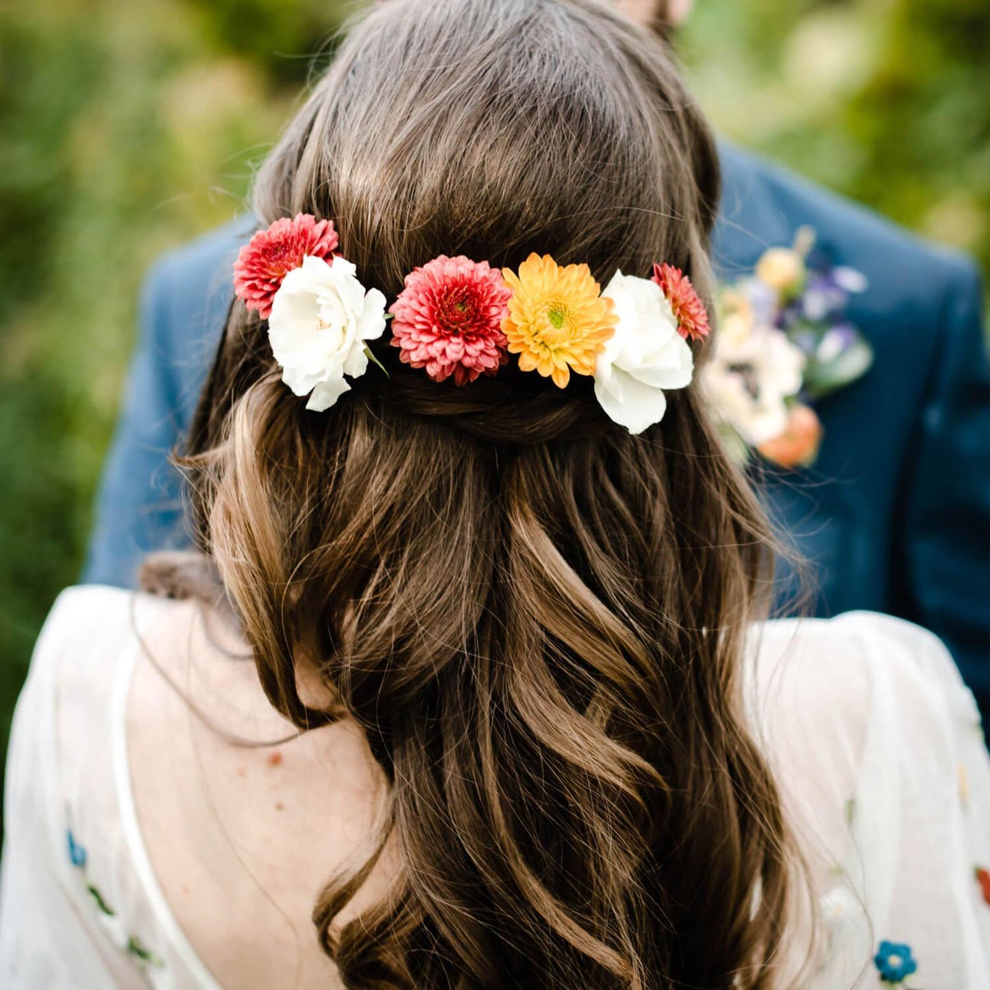 A person with a floral crown made of colorful flowers in their hair, viewed from behind. Order online for wedding & event flowers from the best florist in Toronto near you.