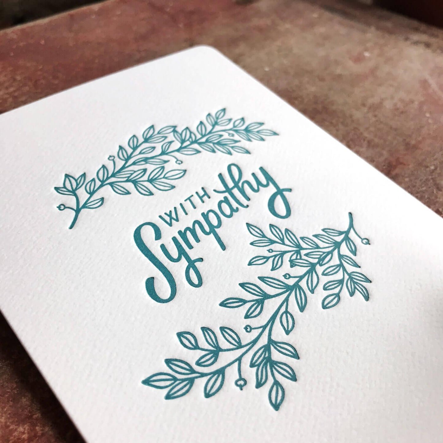 A sympathy card with teal lettering and leaf designs on a white background.Order online for event items from the best florist in Toronto near you.