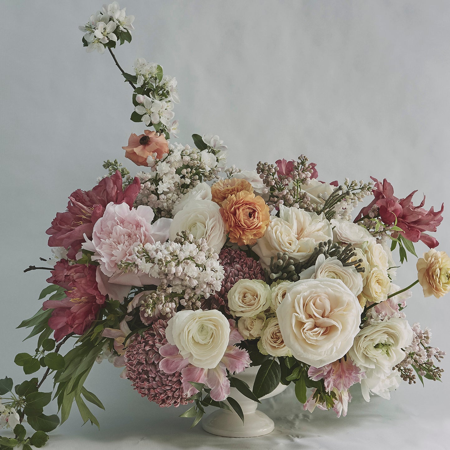 Lush and colorful flower bouquet in a white pedestal vase. Order online for plants & flowers from the best florist in Toronto near you.