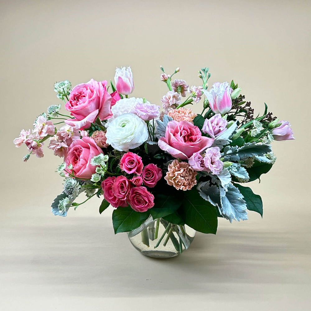 
                      
                        Image of a bouquet featuring airy pastel pink and delicate cream flowers, including a mix of white and pink roses, blush ranunculus, lisianthus, and carnations. Celebrate gender non-binary expression with this sweet palette. Our low and lush table centrepieces for round tables are designed with your colour palette and event ambiance in mind. From the best wedding florist in Toronto Quince Flowers.
                      
                    