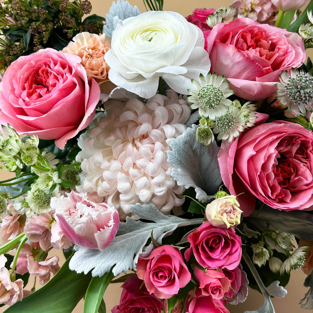 Close-up Image of a bouquet featuring airy pastel pink and delicate cream flowers, including a mix of white and pink roses, blush ranunculus, lisianthus, and carnations. Celebrate gender non-binary expression with this sweet palette. Order online for same-day flower delivery from Toronto's best florist, available near you.