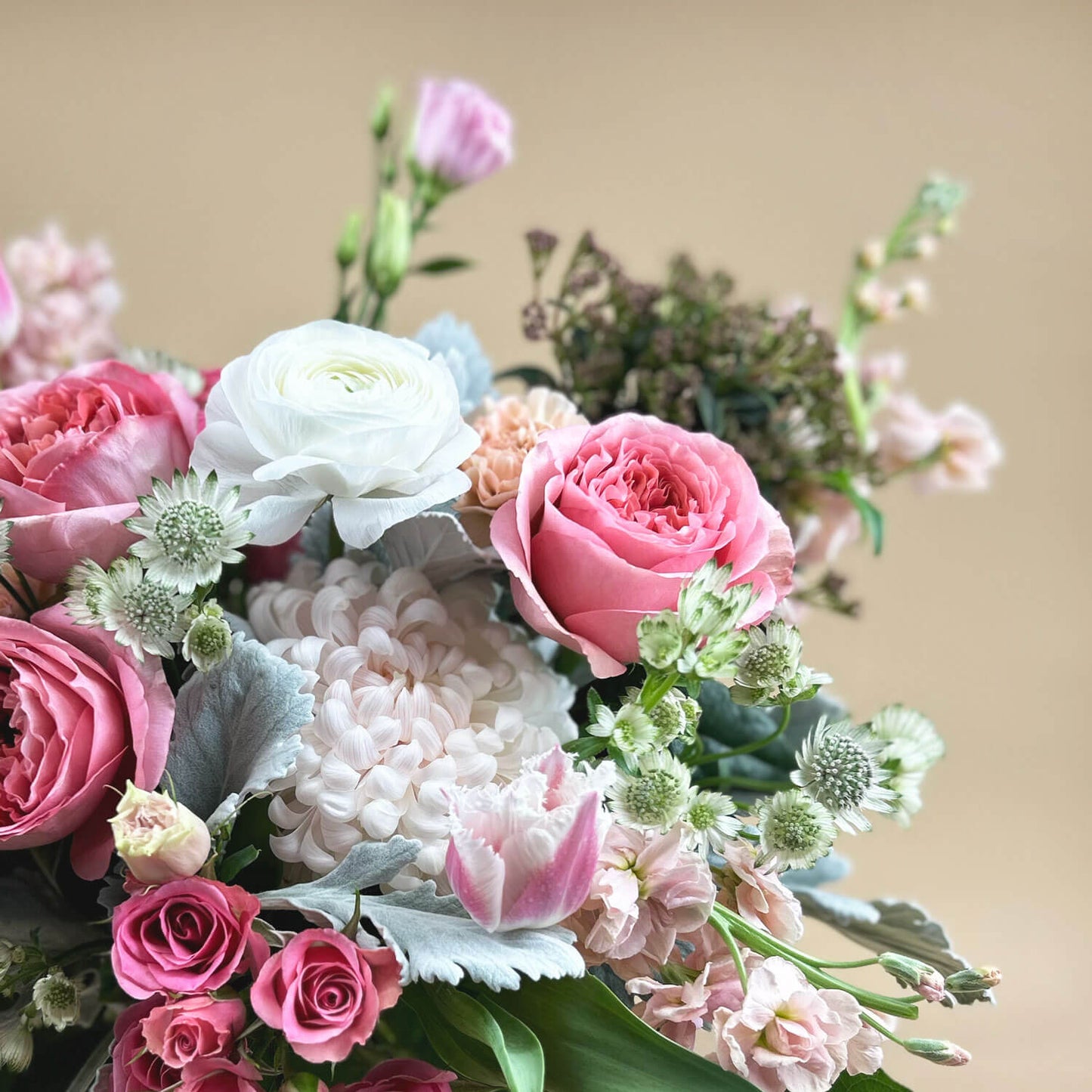 Close-up Image of a bouquet featuring airy pastel pink and delicate cream flowers, including a mix of white and pink roses, blush ranunculus, lisianthus, and carnations. Celebrate gender non-binary expression with this sweet palette. Order online for same-day flower delivery from Toronto's best florist, available near you.