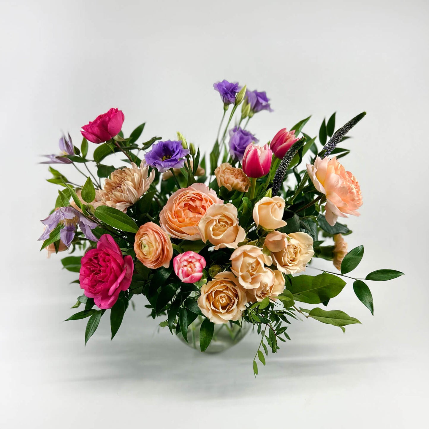 Image of a funny valentines day bouquet with lavender lisianthus, blue clematis, pink, peach, and apricot garden roses, double tulips, apricot ranunculus, and carnations. Order online for same-day flower delivery from Toronto's best florist, available near you.