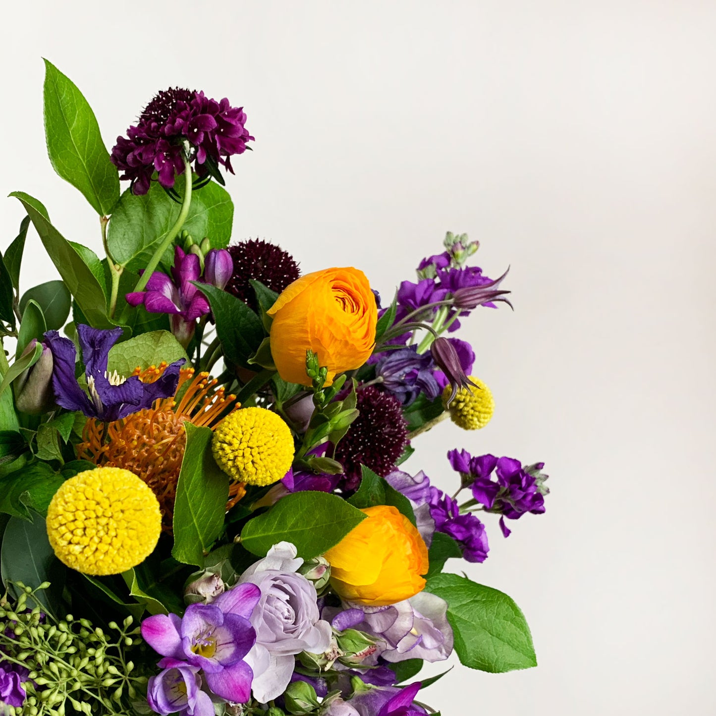 Load image into Gallery viewer, Close-up image of a dynamic bouquet starting with yellows, deepening to purple and mauve, with a touch of acid orange for energy. Order online for same-day flower delivery from Toronto&amp;#39;s best florist, available near you.
