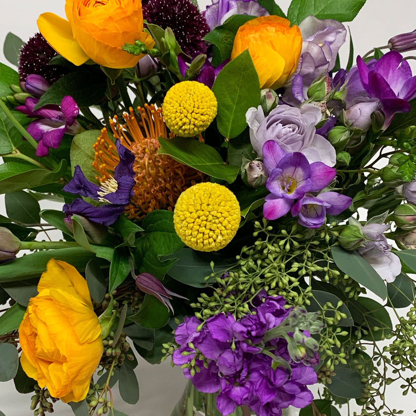 Close-up image of a dynamic bouquet starting with yellows, deepening to purple and mauve, with a touch of acid orange for energy. Order online for same-day flower delivery from Toronto's best florist, available near you.