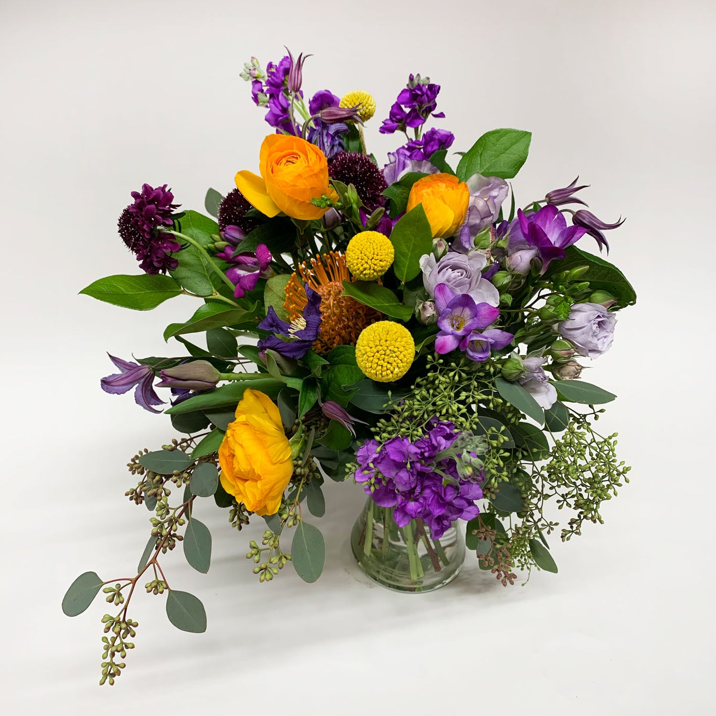 Image of a dynamic bouquet starting with yellows, deepening to purple and mauve, with a touch of acid orange for energy. Order online for same-day flower delivery from Toronto's best florist, available near you.