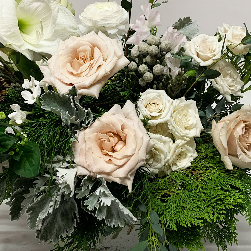 Close-up image of a bouquet featuring shades of linen, off-white, palest pink, winter greens, and eucalyptus, with silver foliage. Order online for same-day flower delivery from the best florist in Toronto near you.