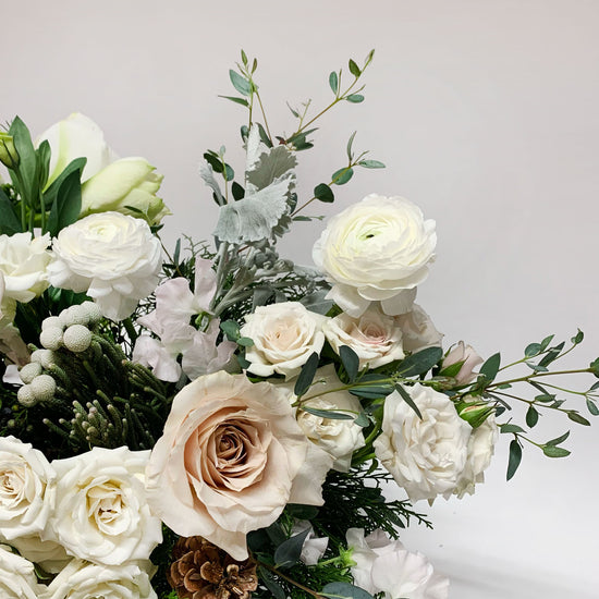 Close-up image of a bouquet featuring shades of linen, off-white, palest pink, winter greens, and eucalyptus, with silver foliage. Order online for same-day flower delivery from the best florist in Toronto near you.