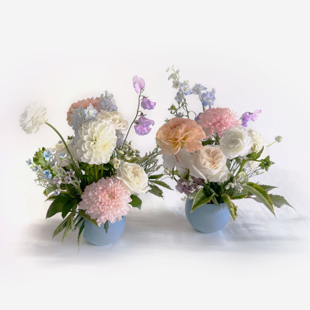 Closeup of soft white, pink and blue flowers. Bloomscape, garland, bud vases, tabletop landscape, centrepieces, deluxe garland. Our low and lush table centrepieces for round tables are designed with your colour palette and event ambiance in mind. From the best wedding florist in Toronto Quince Flowers.