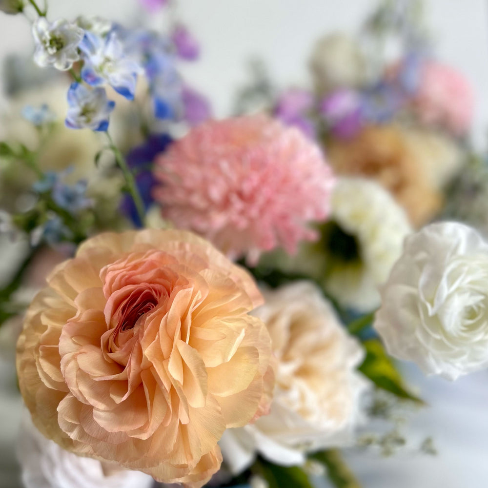 Closeup of soft white, pink and blue flowers. Bloomscape, garland, bud vases, tabletop landscape, centrepieces, deluxe garland. Our low and lush table centrepieces for round tables are designed with your colour palette and event ambiance in mind. From the best wedding florist in Toronto Quince Flowers.