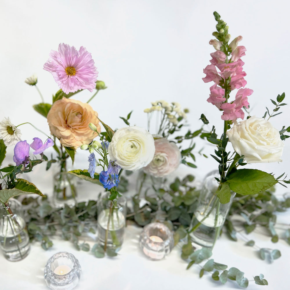 Closeup of pink, peach, white and blue flowers. Bloomscape, garland, bud vases, tabletop landscape, centrepieces, deluxe garland. Enhance your table with as many or as few "Seul Fleur" bud vases, each featuring a single focal flower and accent. Add mini arrangements to create focal points, perfect for the head table. From the best wedding florist in Toronto Quince Flowers.