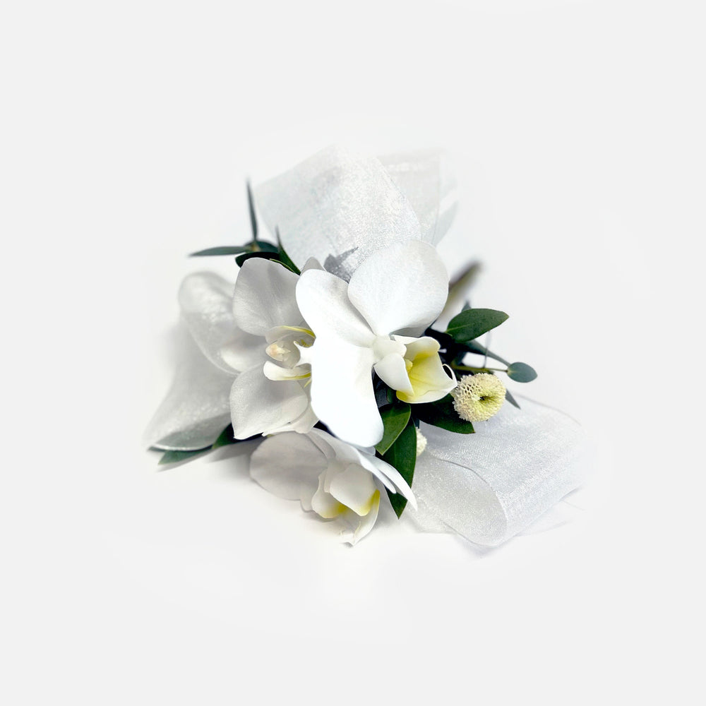 
                      
                        White orchid Corsage – It can be pinned on a woman's clothing, attached with magnets, or worn on the wrist. We like the modern look of a single large, elegant flower like an orchid bloom or garden rose. A cluster of smaller flowers also works! From the best wedding florist in Toronto Quince Flowers.
                      
                    