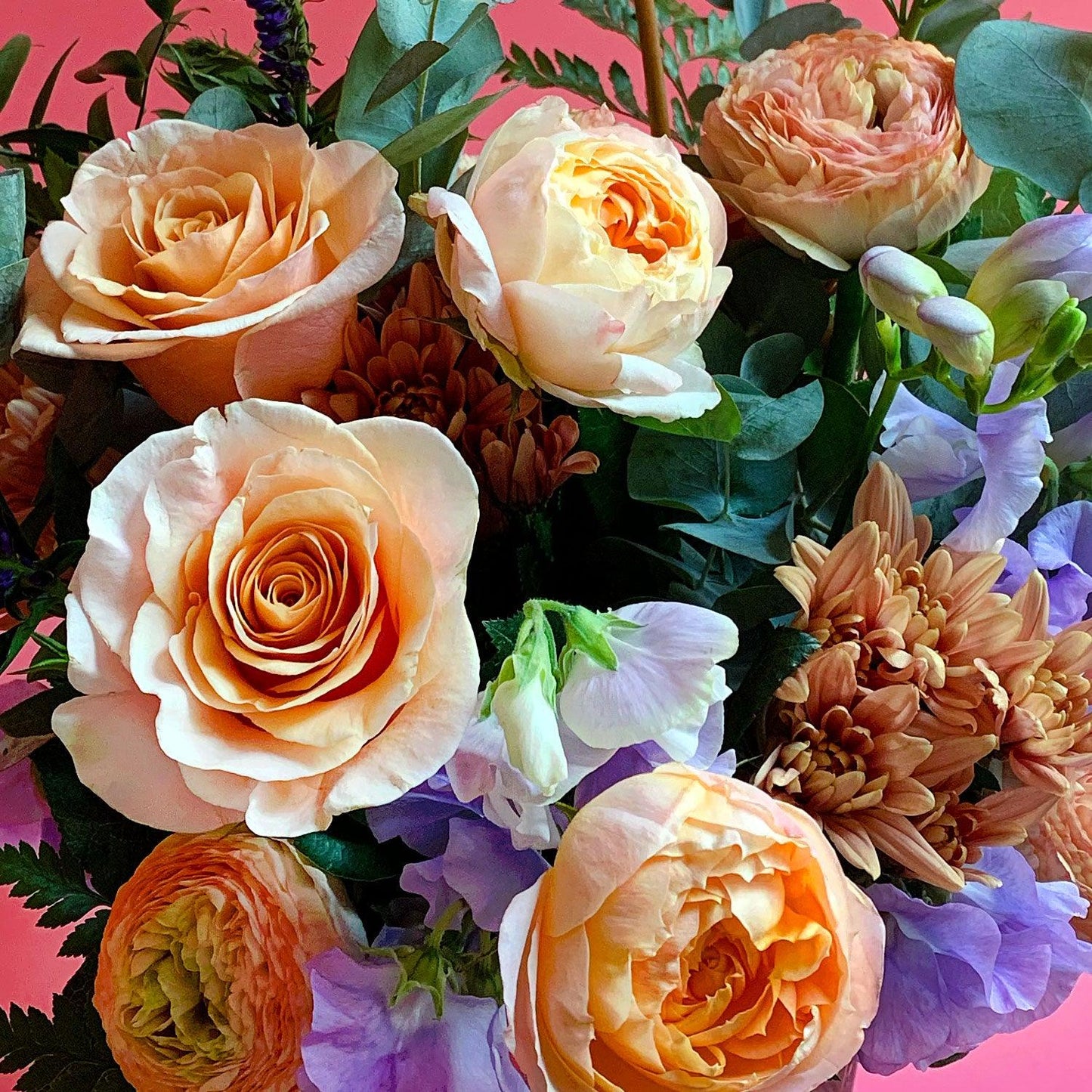 Close-up image of a bouquet with sweet peach and apricot tones, deepening to lavender and blue, with a touch of foliage for freshness. Order online for same-day flower delivery from Toronto's best florist, available near you.