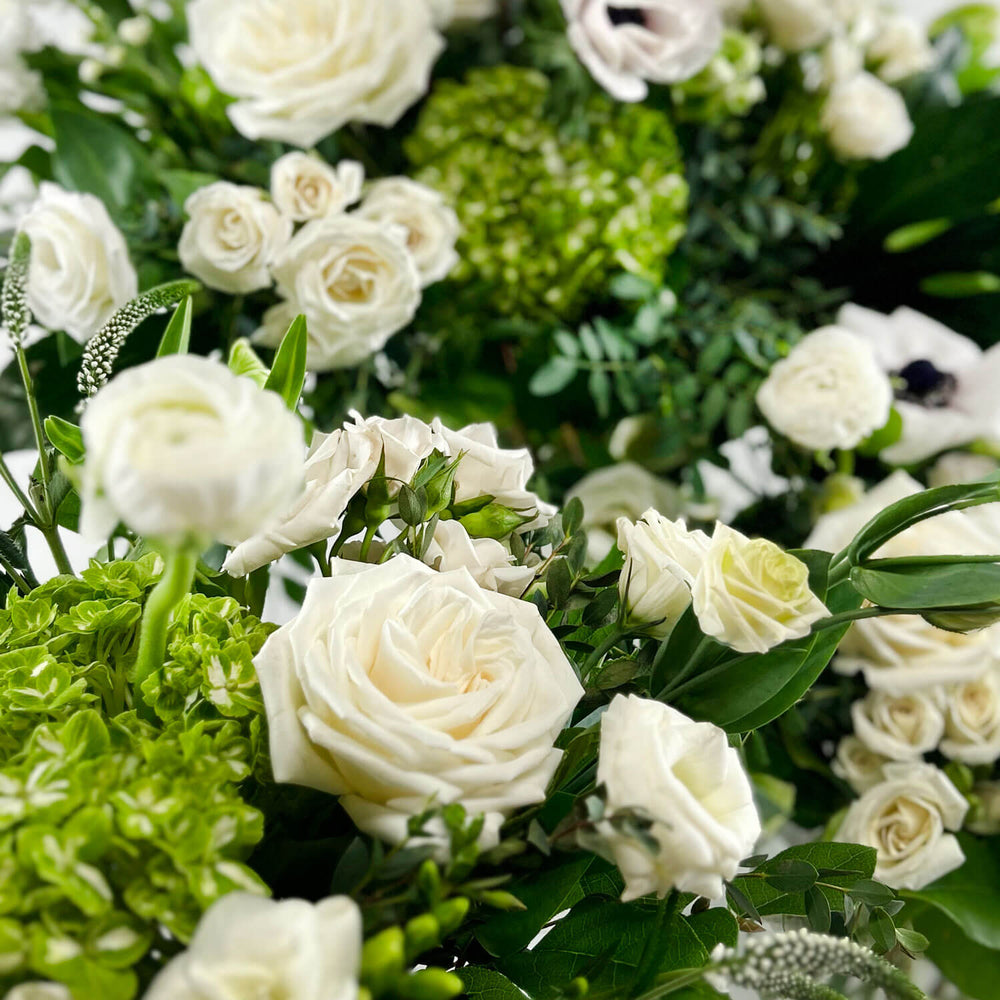 Close-up Image of a romantic bouquet featuring cream and white flowers, including garden roses, parrot tulips, freesia, and ranunculus. Order online for same-day flower delivery from Toronto's best florist, available near you.