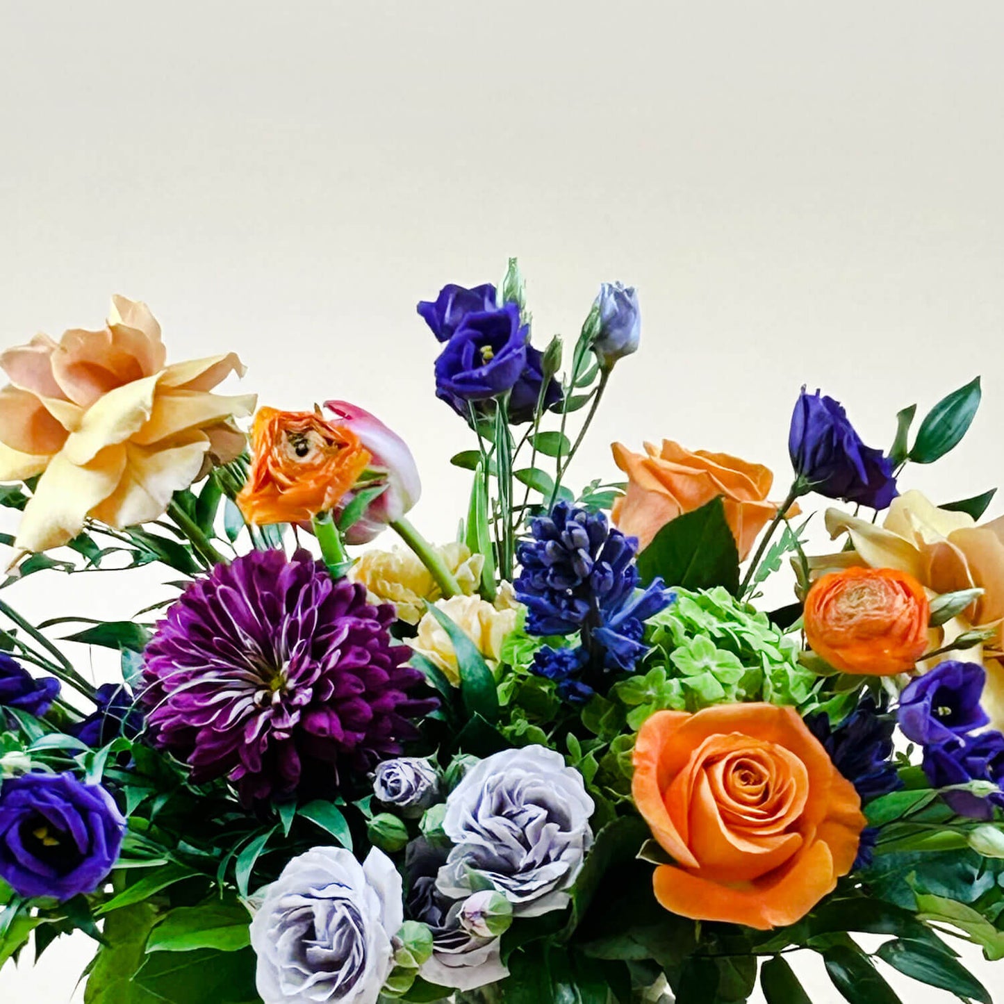 Close-up image of a dynamic bouquet featuring yellow and lavender hues transitioning into deeper purple tones, with accents of citrus orange for vibrancy. A thoughtful and romantic combination. Order online for same-day flower delivery from Toronto's best florist, available near you.