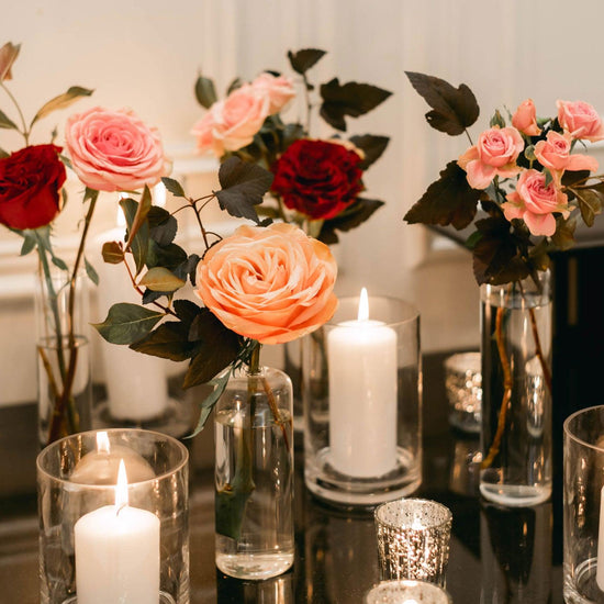 Image of a serene and elegant setting featuring a variety of roses in full bloom, accompanied by lit candles, creating a warm and inviting atmosphere. Order online for same-day flower delivery from the best florist in Toronto near you.