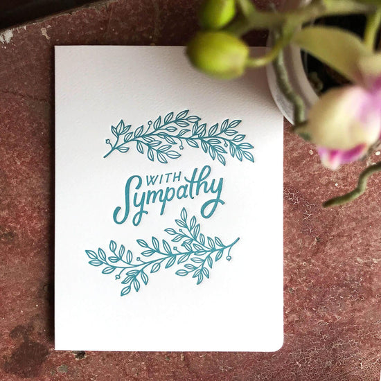 A sympathy card with teal lettering and leaf designs on a white background.Order online for event items from the best florist in Toronto near you.
