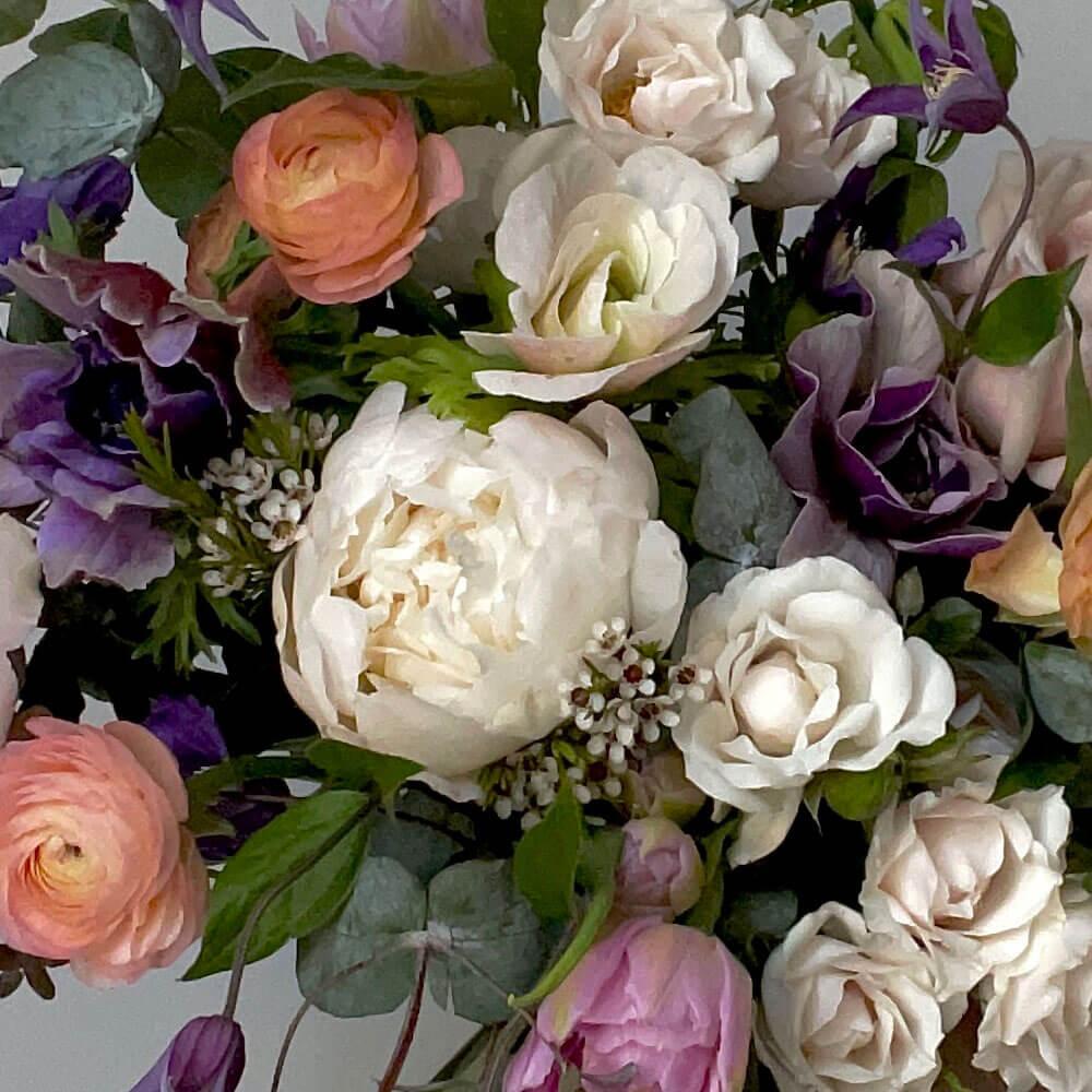 Close-up Image of a bouquet inspired by dusky lilac hues, mostly white with moody lavender, rose, and apricot flowers. A thoughtful and romantic combination. Order online for same-day flower delivery from Toronto's best florist, available near you.